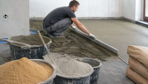 Travailleur nivelant une chape de béton